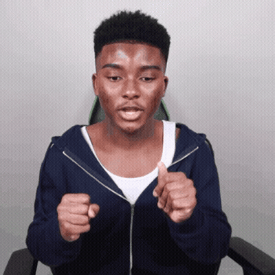 A Young Man Wearing A Blue Hoodie And A White Tank Top Is Giving A Thumbs Up GIF