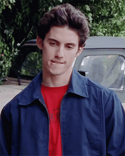 A Young Man Wearing A Blue Jacket And A Red T-Shirt Is Standing In Front Of A Truck GIF