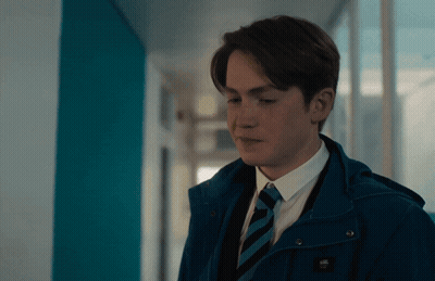 A Young Man Wearing A Blue Jacket And Tie With The Word Vans On It GIF