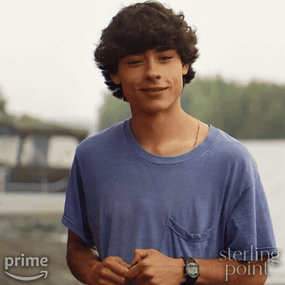 A Young Man Wearing A Blue Shirt And A Watch Is Standing In Front Of A Sign That Says Sterling Point GIF