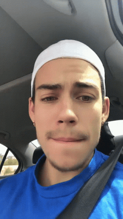 A Young Man Wearing A Blue Shirt And A White Headband Looks At The Camera GIF