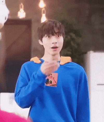 A Young Man Wearing A Blue Sweater Is Standing In A Room . GIF