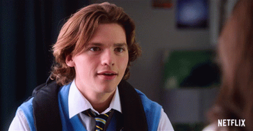 A Young Man Wearing A Blue Vest And Tie With A Netflix Logo On The Bottom GIF