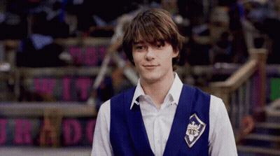 A Young Man Wearing A Blue Vest With A Badge That Says 25 On It GIF