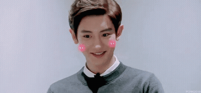 A Young Man Wearing A Bow Tie And A Sweater Is Smiling With Pink Hearts On His Cheeks . GIF