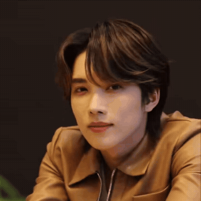 A Young Man Wearing A Brown Leather Jacket Is Smiling . GIF