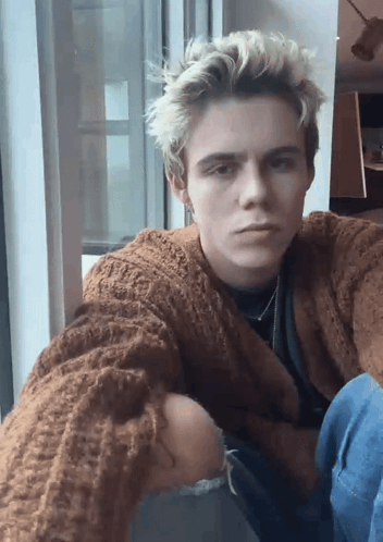 A Young Man Wearing A Brown Sweater Takes A Selfie GIF