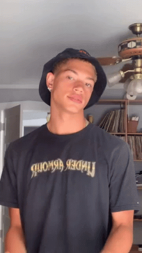 A Young Man Wearing A Bucket Hat And A T-Shirt That Says Under Armour GIF