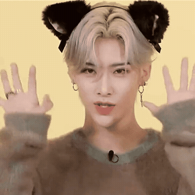 A Young Man Wearing A Cat Ear Headband Is Making A Cat Face With His Hands . GIF