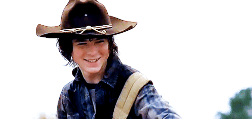 A Young Man Wearing A Cowboy Hat And A Plaid Shirt Smiles . GIF