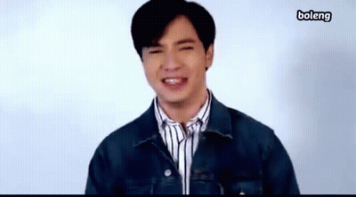 A Young Man Wearing A Denim Jacket And Striped Shirt Is Smiling . GIF