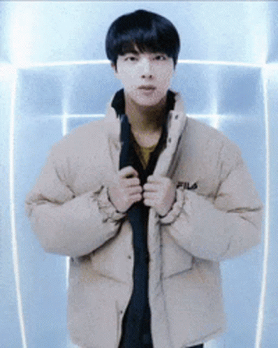 A Young Man Wearing A Fila Jacket Is Standing In Front Of A Blue Wall GIF