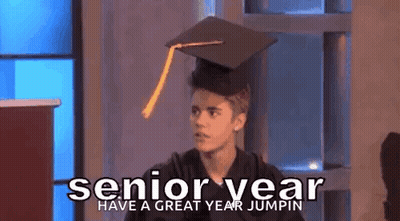A Young Man Wearing A Graduation Cap And Gown Is Standing In Front Of A Podium . GIF