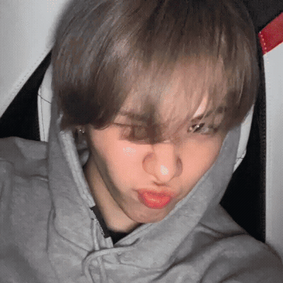 A Young Man Wearing A Gray Hoodie Is Making A Funny Face . GIF