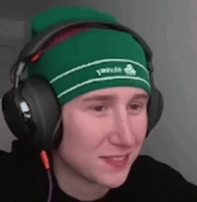 A Young Man Wearing A Green Beanie And Headphones Is Smiling . GIF