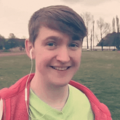 A Young Man Wearing A Green Shirt And A Red Jacket Is Smiling . GIF