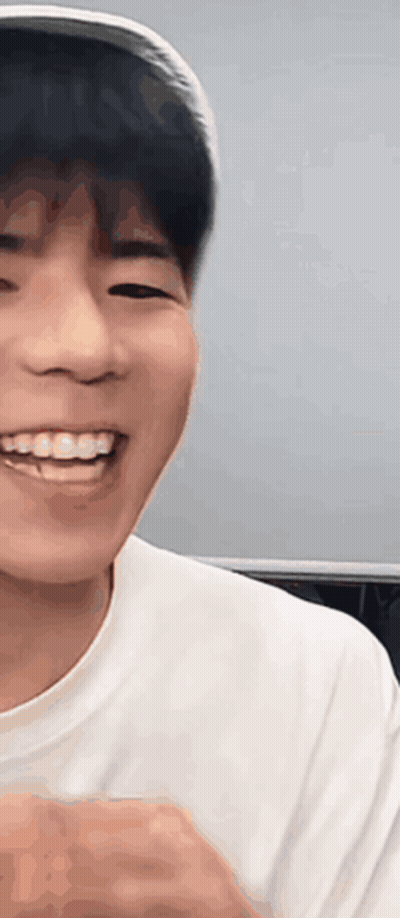A Young Man Wearing A Hat And A White Shirt Is Smiling And Looking At The Camera . GIF