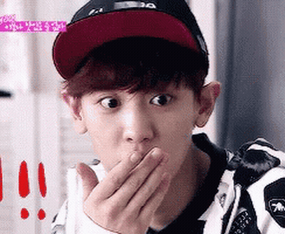 A Young Man Wearing A Hat Is Covering His Mouth With His Hands GIF