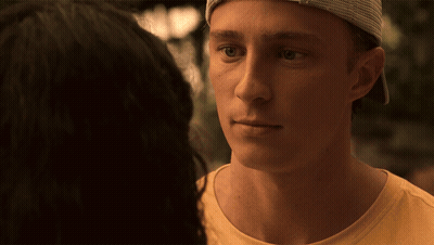 A Young Man Wearing A Hat Looks At A Woman In A Yellow Shirt GIF
