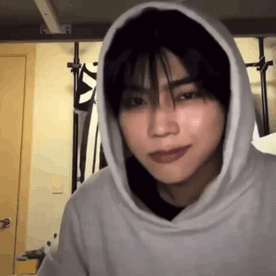 A Young Man Wearing A Hoodie Is Looking At The Camera In A Room . GIF