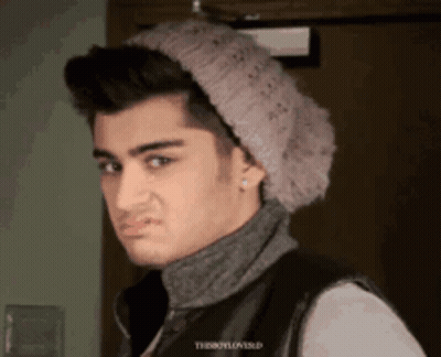 A Young Man Wearing A Knitted Hat And A Turtleneck Is Making A Face GIF