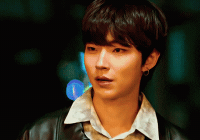 A Young Man Wearing A Leather Jacket And A White Shirt Looks At The Camera GIF