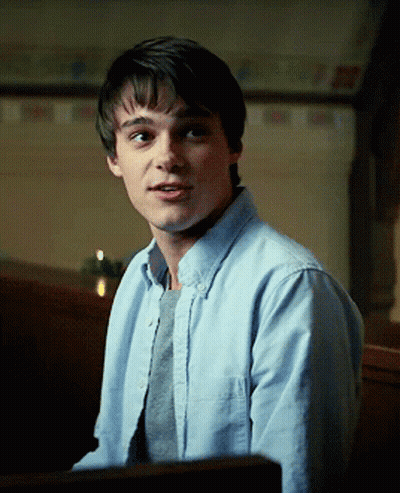 A Young Man Wearing A Light Blue Shirt And A Grey Sweater GIF