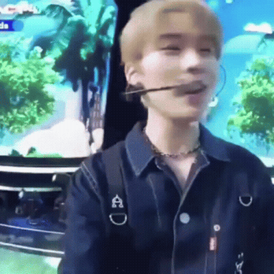 A Young Man Wearing A Microphone And A Necklace Is Sitting In Front Of A Tv . GIF
