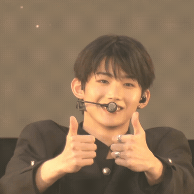 A Young Man Wearing A Microphone Giving A Thumbs Up Sign GIF