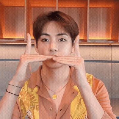 A Young Man Wearing A Necklace And A Shirt Is Making A Funny Face GIF