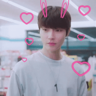 A Young Man Wearing A Necklace With The Number 1 On It Surrounded By Pink Hearts GIF