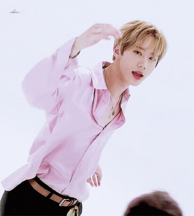 A Young Man Wearing A Pink Shirt And Black Pants Is Standing In Front Of A White Background GIF