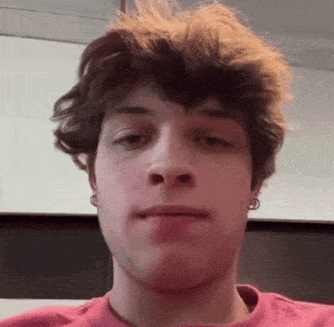 A Young Man Wearing A Pink Shirt Is Making A Funny Face . GIF