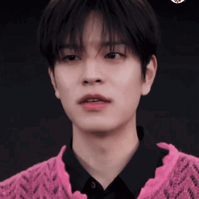 A Young Man Wearing A Pink Sweater And A Black Shirt Is Looking At The Camera . GIF