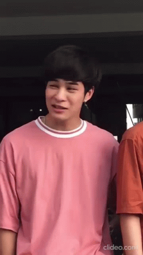 A Young Man Wearing A Pink T-Shirt Is Standing Next To Another Young Man . GIF