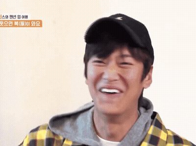 A Young Man Wearing A Plaid Shirt And A Black Hat Smiles GIF