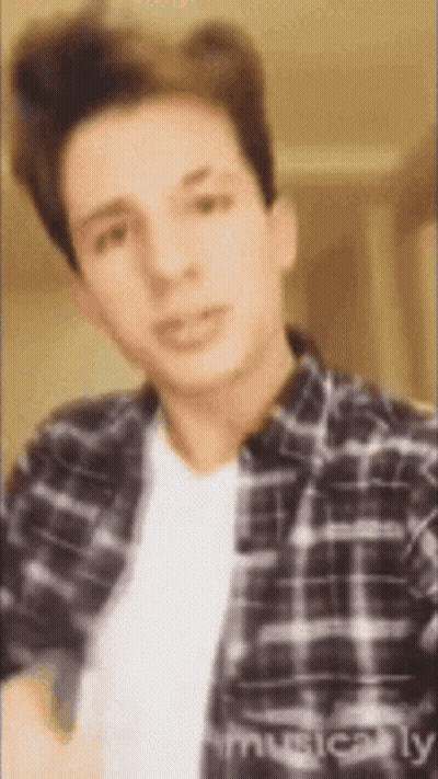 A Young Man Wearing A Plaid Shirt And A White Shirt . GIF