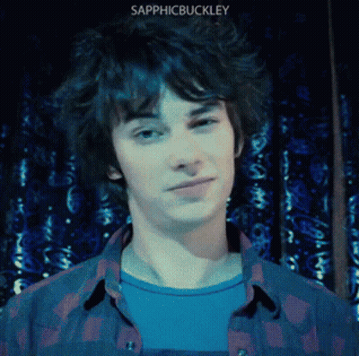 A Young Man Wearing A Plaid Shirt With The Name Sapphicbuckley On The Bottom Right GIF