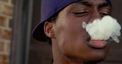 A Young Man Wearing A Purple Hat Is Blowing Smoke Out Of His Mouth GIF