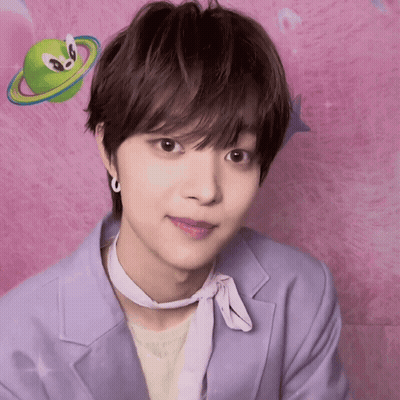 A Young Man Wearing A Purple Jacket And A White Scarf Looks At The Camera In Front Of A Pink Background GIF