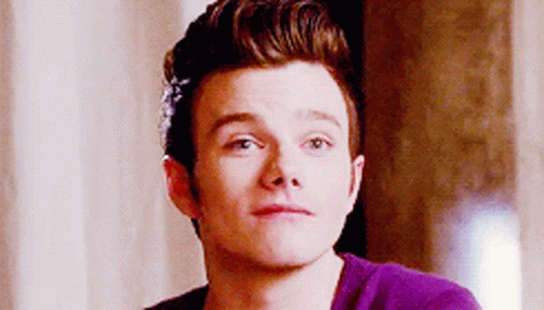 A Young Man Wearing A Purple Shirt Is Looking At The Camera . GIF