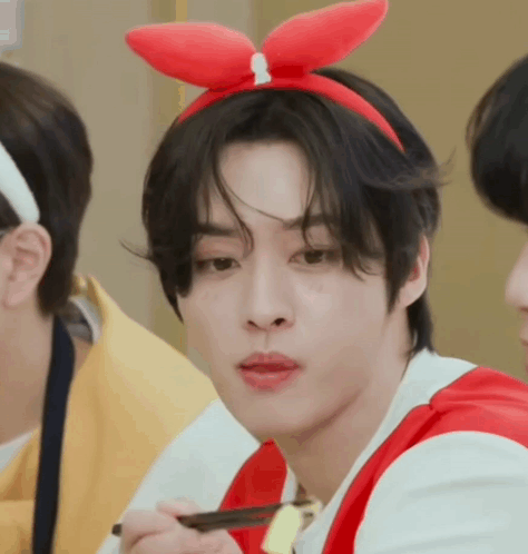 A Young Man Wearing A Red Bunny Ear Headband Is Eating With Chopsticks . GIF