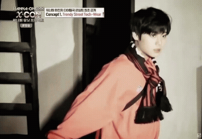 A Young Man Wearing A Red Jacket And Scarf Is Standing Next To A Staircase . GIF