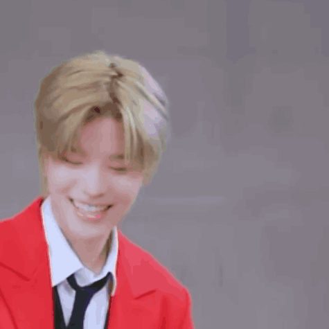 A Young Man Wearing A Red Jacket And Tie Is Smiling . GIF