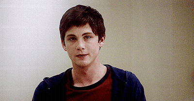 A Young Man Wearing A Red Shirt And A Blue Hoodie Is Standing In Front Of A Wall . GIF