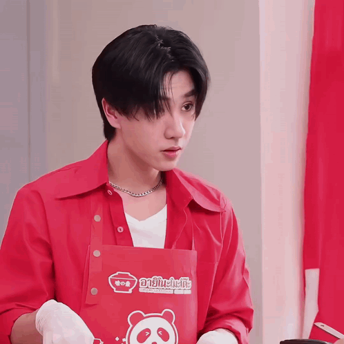 A Young Man Wearing A Red Shirt And An Apron With A Panda On It GIF