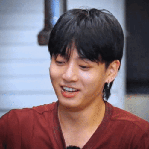 A Young Man Wearing A Red Shirt And Earrings Smiles GIF