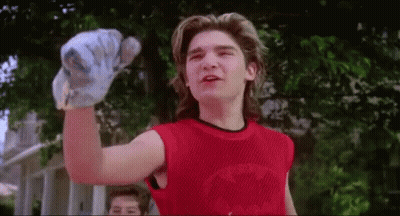 A Young Man Wearing A Red Tank Top Is Holding A Baseball Bat In His Hand . GIF