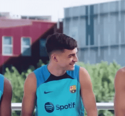 A Young Man Wearing A Spotify Shirt Is Smiling While Standing Next To A Group Of Young Men . GIF