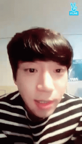 A Young Man Wearing A Striped Shirt Is Making A Peace Sign GIF